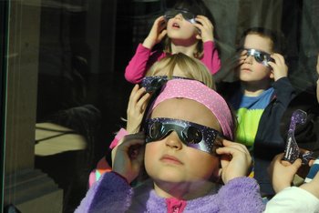 Kinder, die eine Sonnenfinsternisbrille aufhaben, schauen nach oben